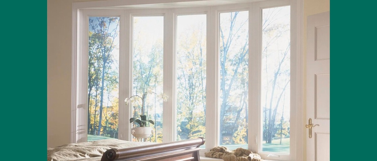 Luxury Utah bedroom with five tall white-framed picture windows showcasing autumn trees and natural light, featuring a wooden sleigh bed and white orchid arrangement